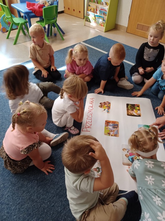 Dzieci siedza na dywanie i tworza kodeks przedszkolaka