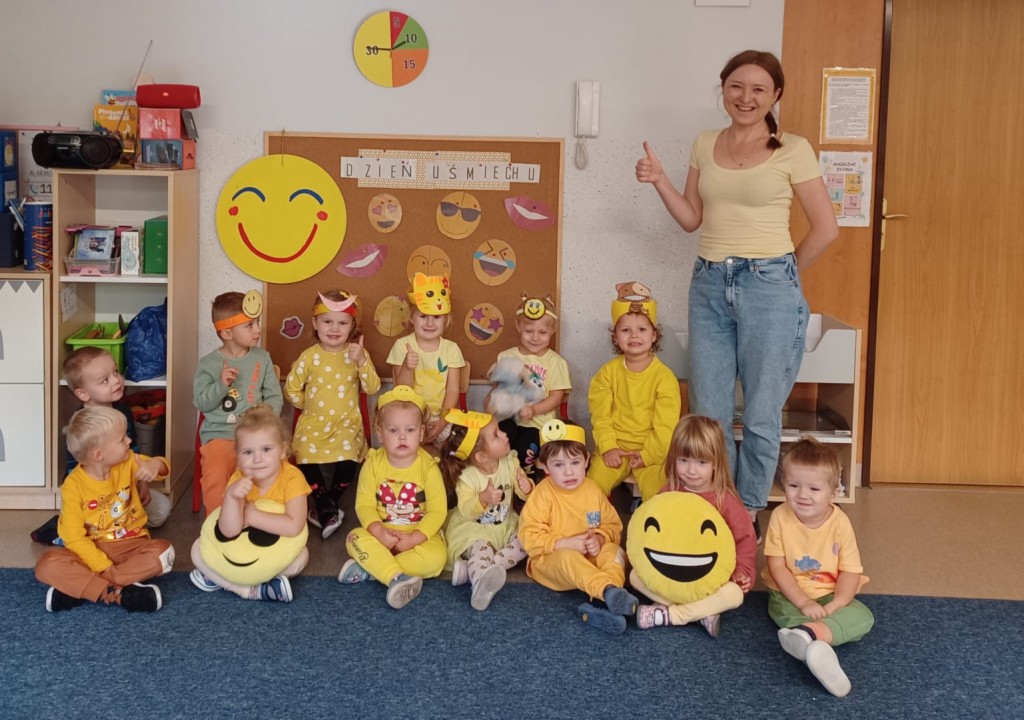 Dzieci i wychowawczyni ubrani na żółto pozuja do zdjecia z okazji dnia umiechu