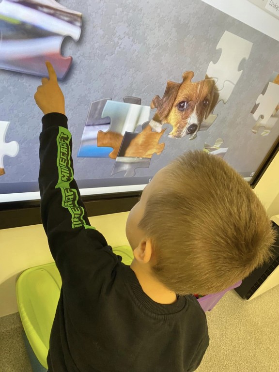 Chłopiec układa pieska na tablicy interaktywnej