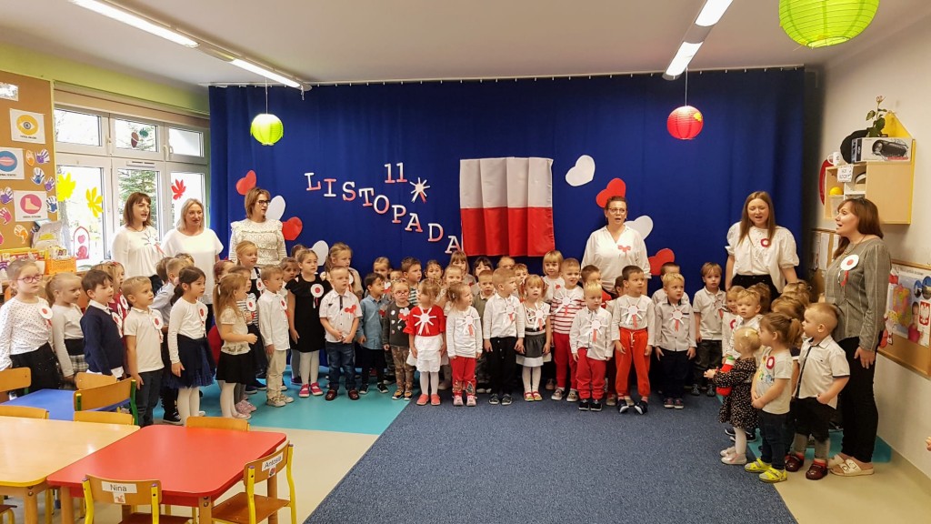 Przedszkolaki raem z nauczycielkami i pania dyrektor spiewaja hymn polski