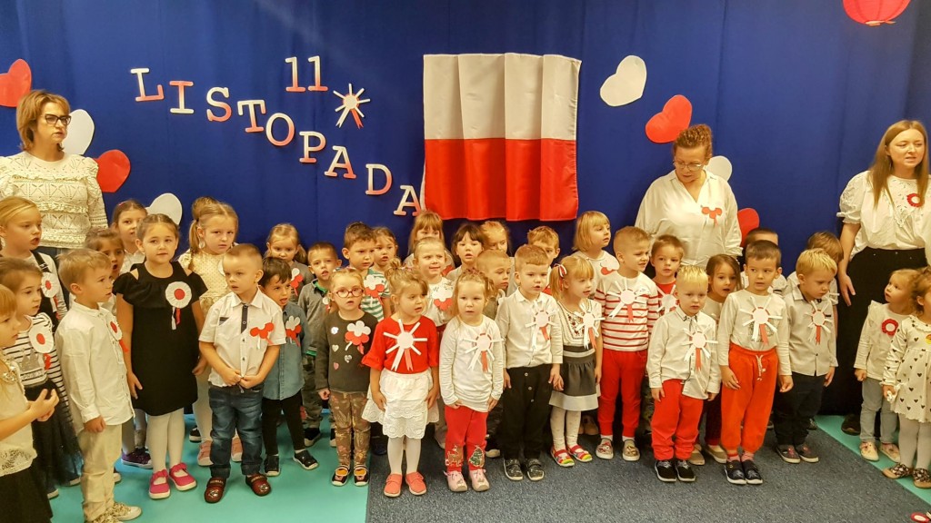 Dzieci i ich nauczycielki spiewaja hymn polski z okazji dnia niepodleglosci