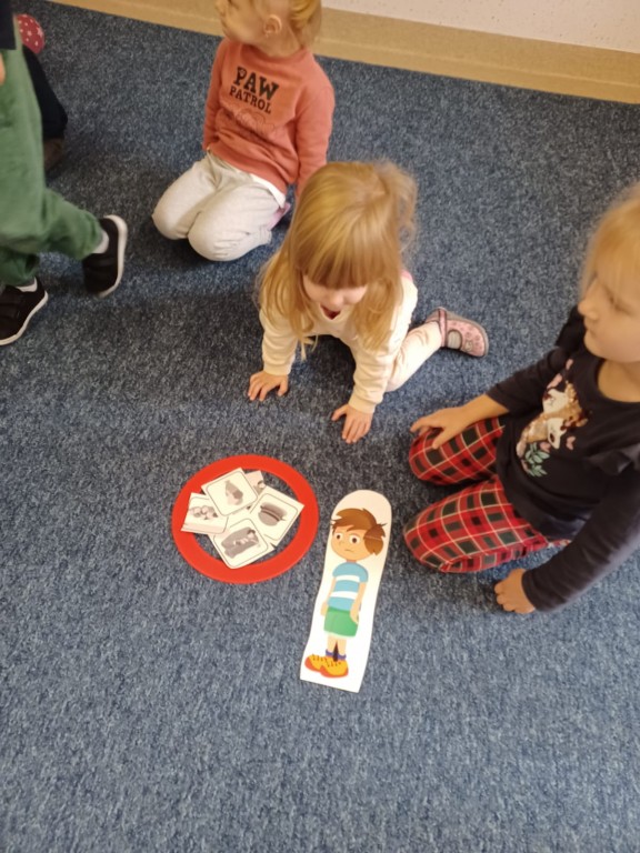 Dzieci siedza na dywanie i opisuja niezdrowe czynnosci
