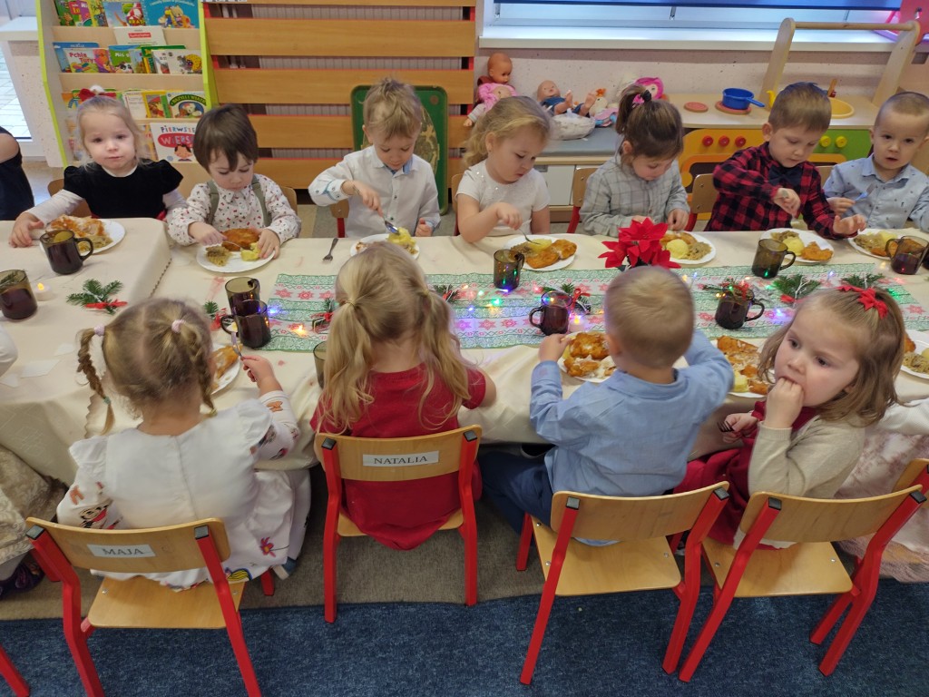 dzieci siedza przy stole i jedza swiateczny objad