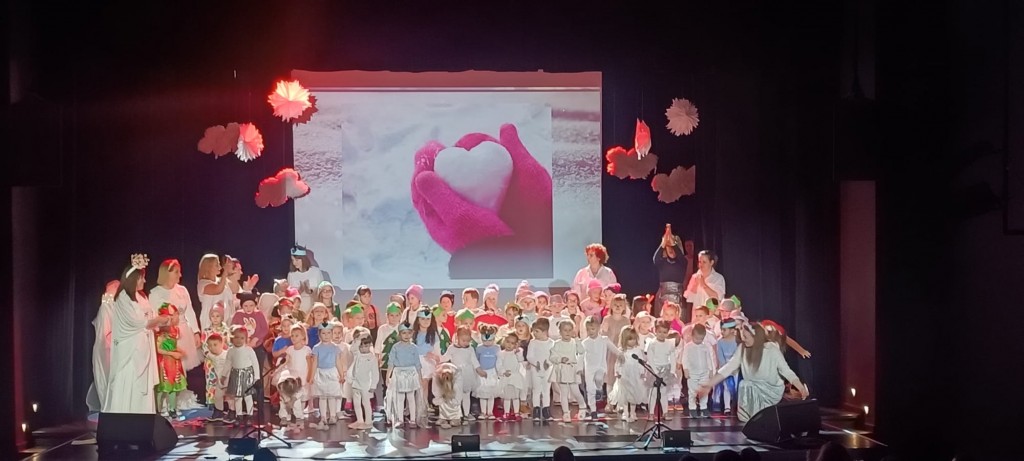 Dzieci stoja na scenie i spiewaja zimowa piosenke