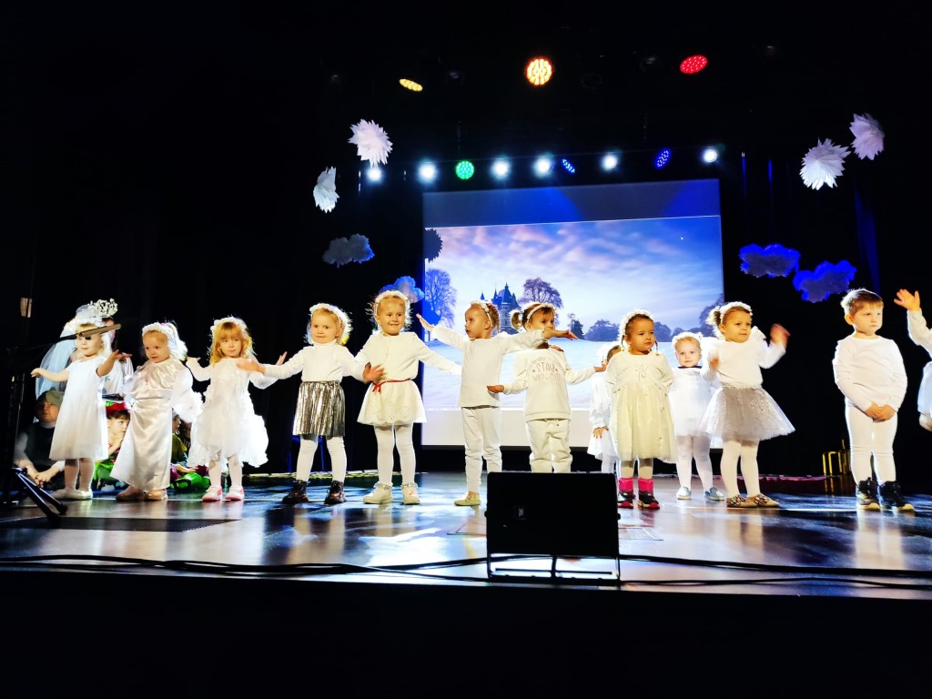 Dzieci ubrane na bialo spiewaja piosenke o zimie