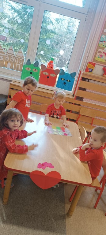 Dzieci siedza przy stoliku i klasyfikuja serca do odpowiedniego koloru