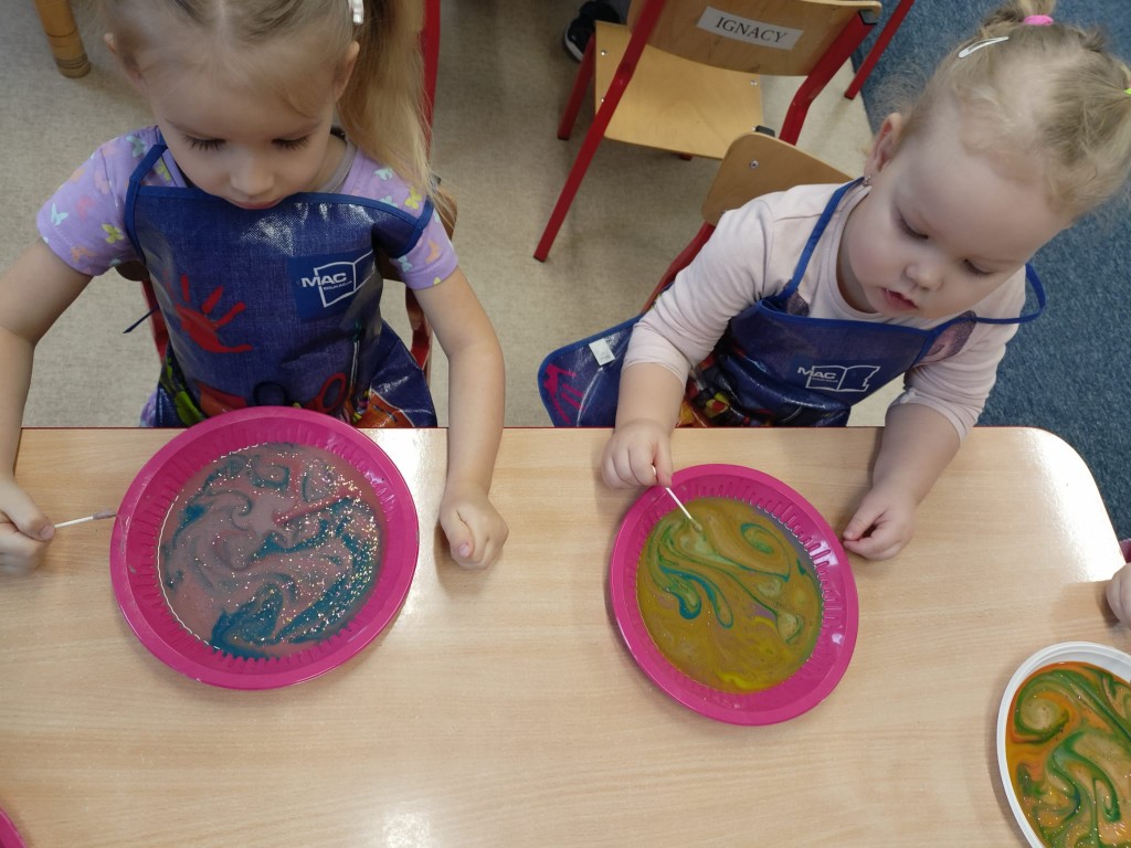 dwie dziewczynki mieszaja farby patyczkiem higienicznym