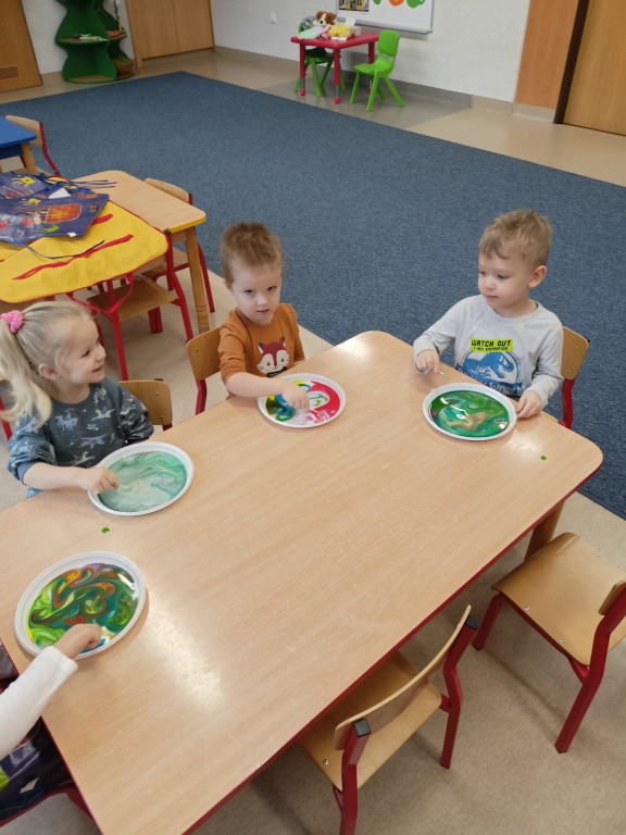 dzieci siedza przy stolikach i mieszaja farby na talerzykach