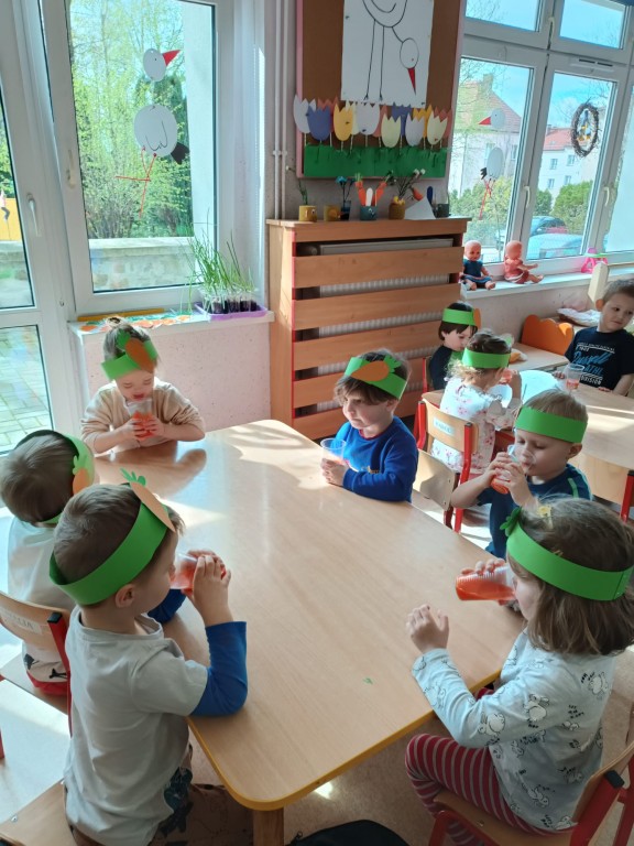 dzieci siedza [rzy stolikach i pija sok marchewkowy