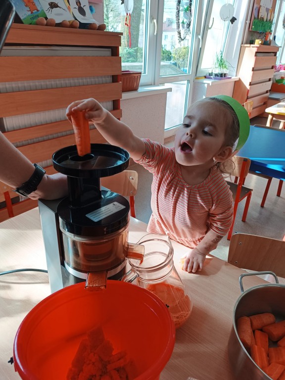 dziewczynka wklada marchewke do sokowirowki