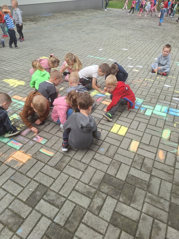 Dzieci malują kredą po chodniku