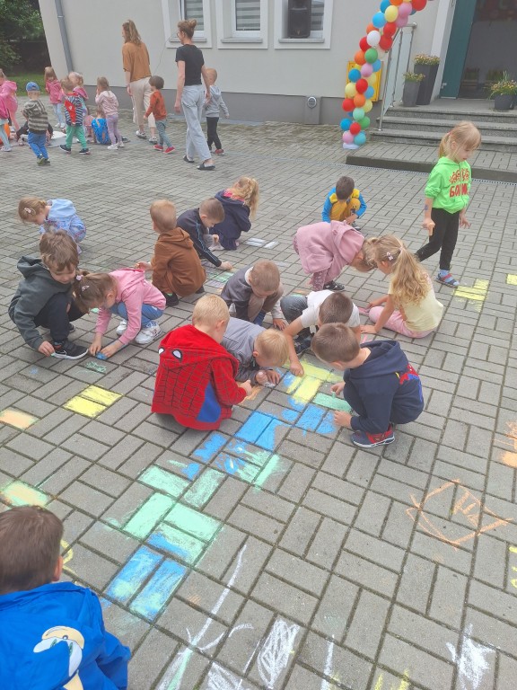 Dzieci malują kredą po chodniku
