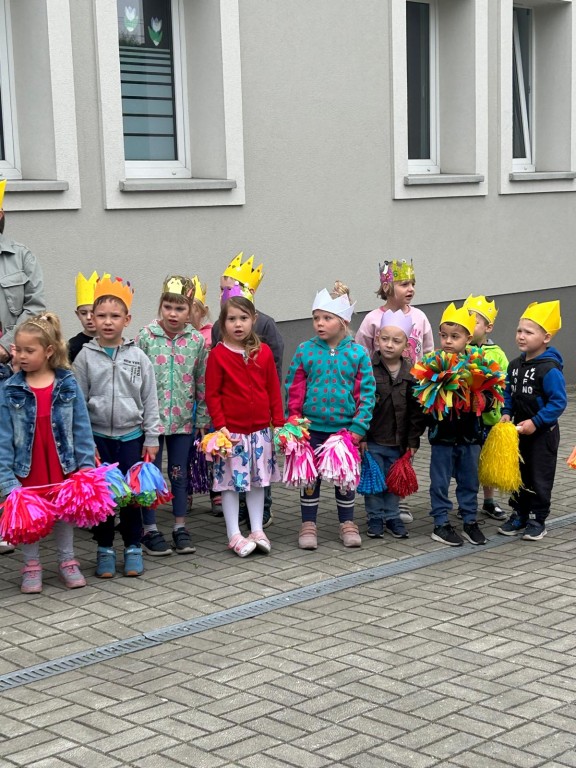 Dzieci stoją na placu przedszkolnym z koronami na głowach