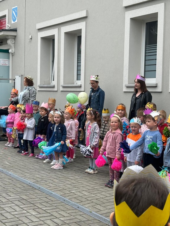 Dzieci stoją na placu przedszkolnym z koronami na głowach 