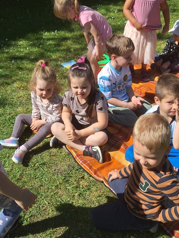 Dzieci siedzą na kocu na trawie