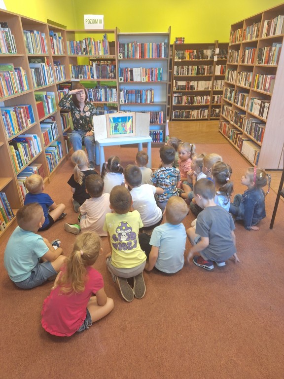 Dzieci siedzą na dywanie w bibliotece 