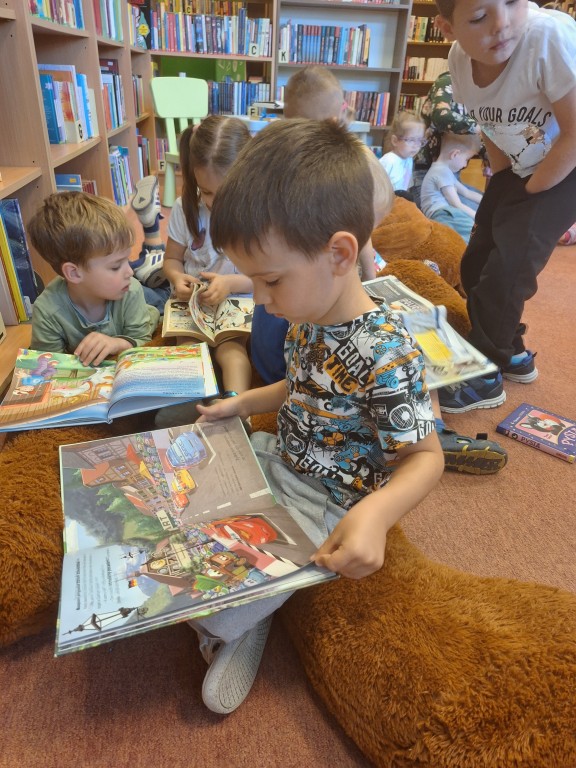 Dzieci oglądają na dywanie książeczki 