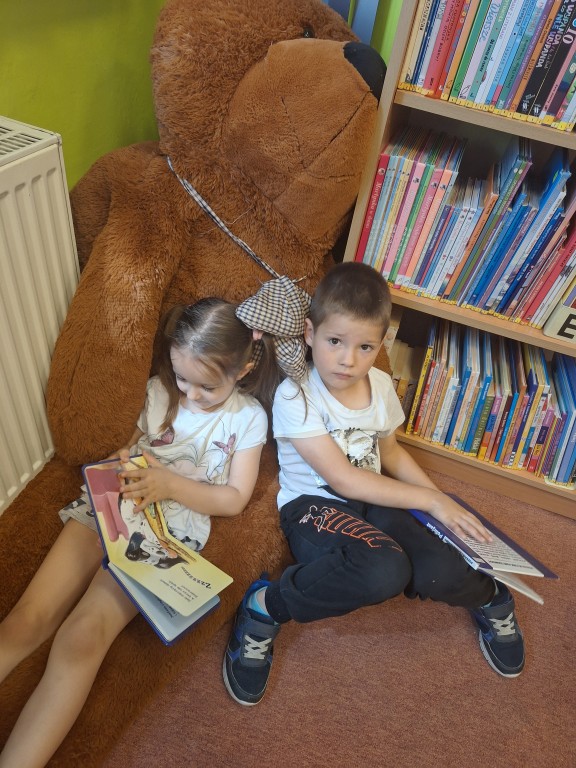 Dzieci siedzą na dywanie i oglądają książeczki 