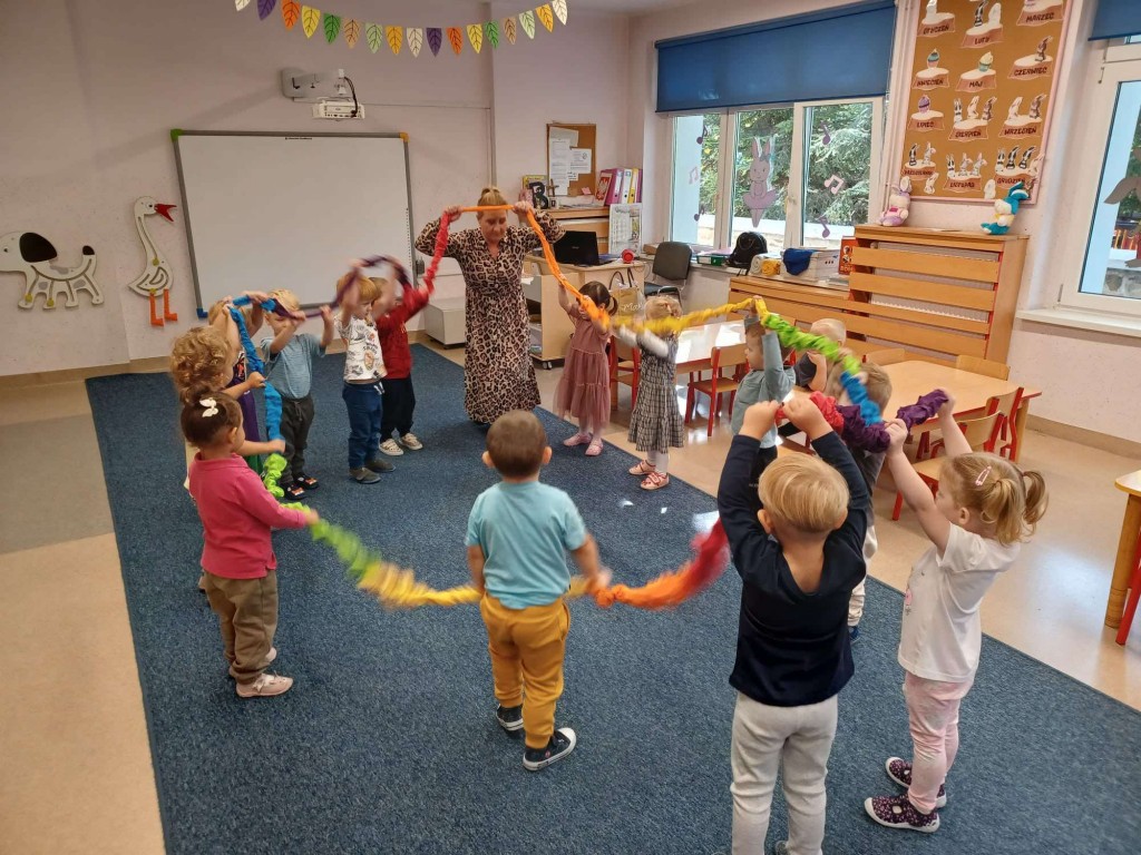 Dzieci stoją w kole trzymając gumę sensoryczną